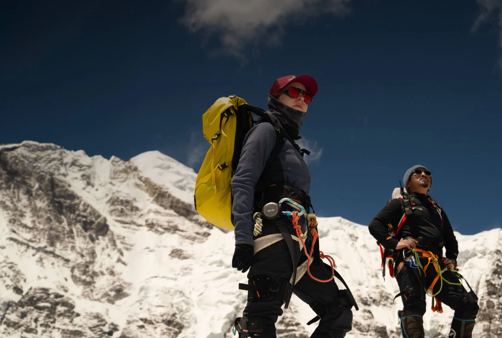 Dos alpinistas con exoesqueletos Hypershell sobre la nieve, con montañas del Himalaya al fondo.